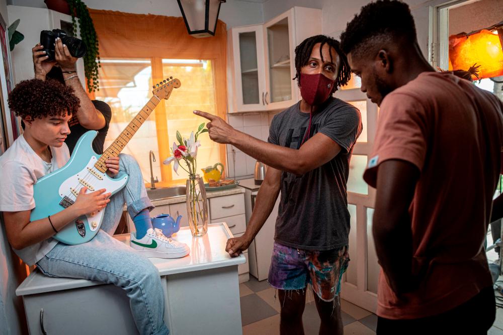 Ghanaian-Romanian musician, Wanlov the Kubolor (C), gives some directions to Sofie (L), a Ghanian songwriter, and to the filmmaker before the filming of a music video in Accra, Ghana, on April 10, 2021. –AFP