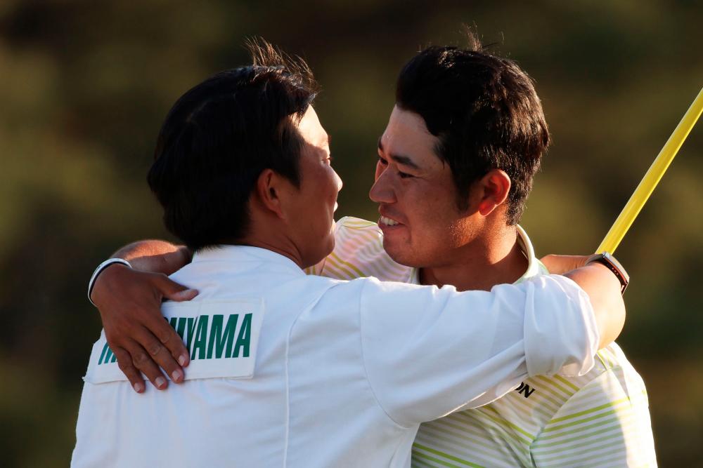 Hideki Matsuyama (R) hugs his caddie, Shota Hayafuji, on the 18th green after winning the Augusta Masters. – AFPPIX