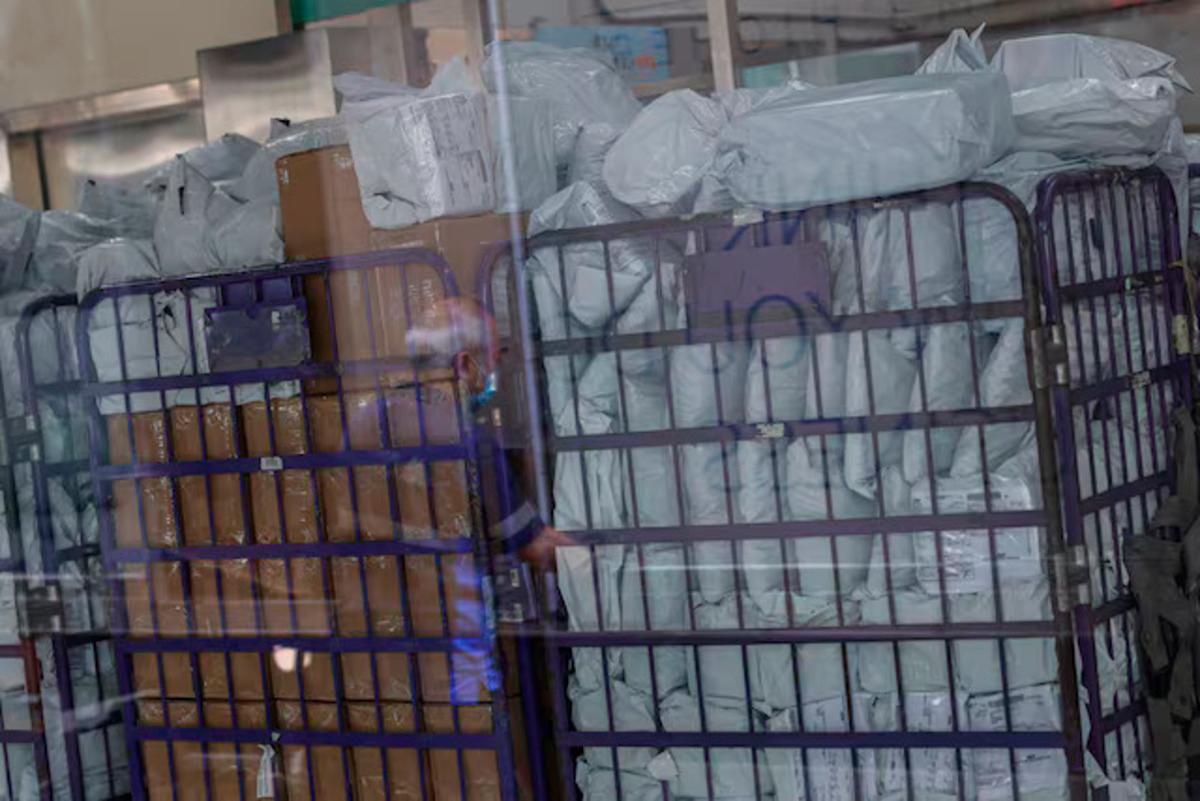 Parcels waiting to be processed are seen through a glass as a delivery worker’s reflection appears on it in a post office, as Hong Kong Post stops certain U.S.-bound shipments since April 27 due to new U.S. tariff rules, in Hong Kong, China. - REUTERS