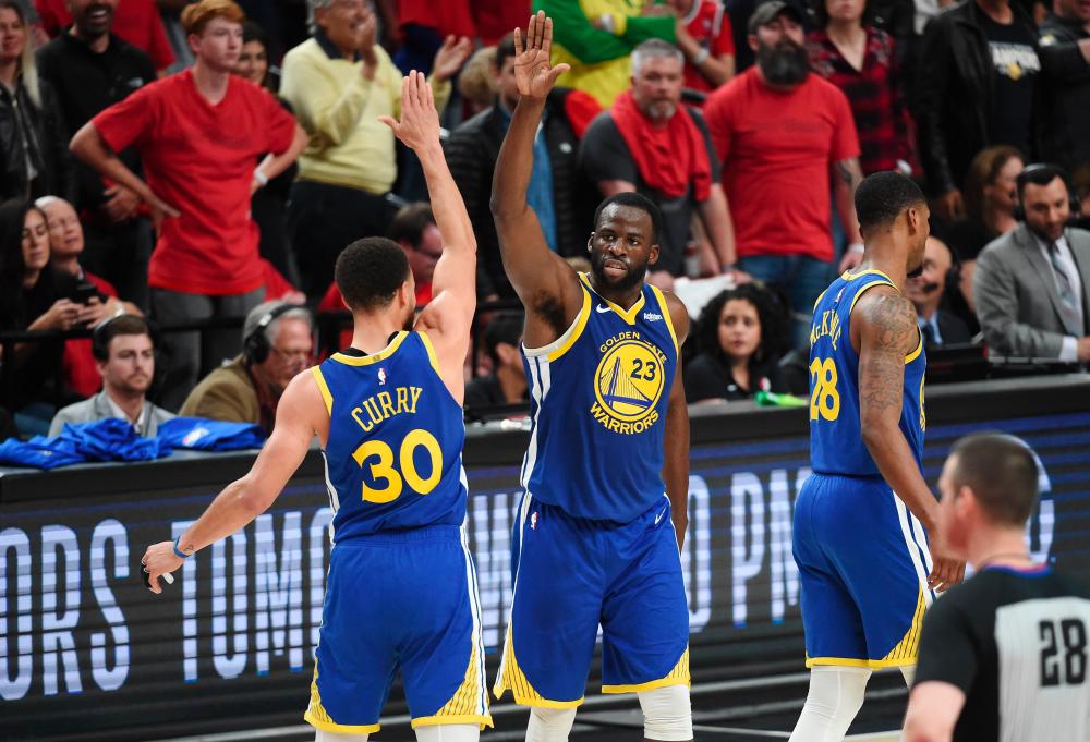Stephen Curry #30 of the Golden State Warriors high fives Draymond Green #23 during the second half against the Portland Trail Blazers in game four of the NBA Western Conference Finals at Moda Center on May 20, 2019 in Portland, Oregon. - AFP