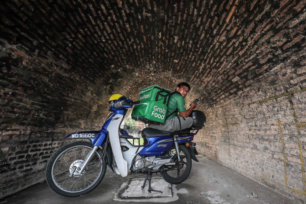 Mior Syamel is seen patiently waiting for food orders from customers at an empty tunnel in Kuala Lumpur since he is sensitive to loud noises. - ADIB RAWI YAHYA/THESUN