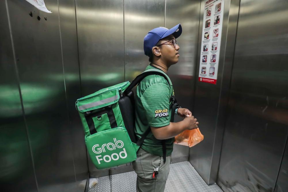 $!Syamel was seen to be at a lift holding the food to deliver it to his customer. - ADIB RAWI YAHYA/THESUN