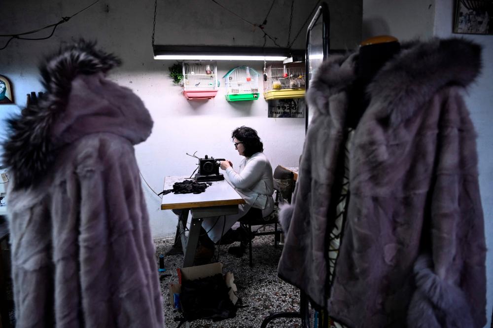 This picture taken on February 1, 2023, shows Mary, 59, as she sews a fur coat in a fur workshop in the northern Greek town of Siatista. AFPPIX