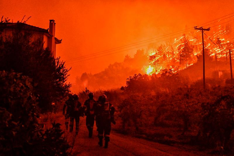 Firefighters walk on a road as a wild fire rages in the village of Ano Loutro, south of Athens, on September 30, 2024. At least two people were found dead and seven villages were evacuated due to the fire. - AFPpix