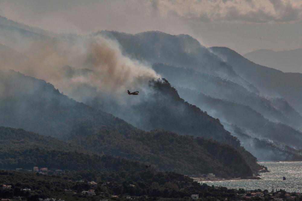 Firefighting planes fly over the coast line during forest fires near the village of Alepochori on May 20, 2021. Scores of Greek villagers were evacuated early on May 20, 2021 as a forest fire raged overnight around the protected wildlife habitat of Mount Geraneia, the fire department said, with no injuries immediately reported. – AFP