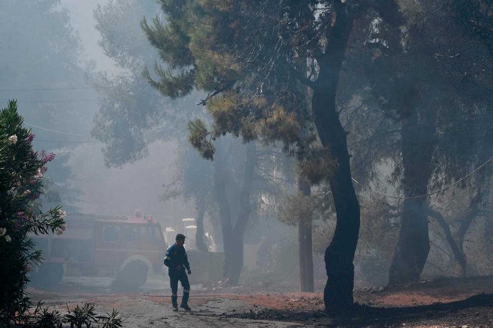 A man walks past a firefighters’ truck during a forest fire in Dionysos, north east of Athens, on July 27, 2021. -AFP