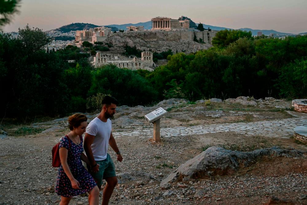 $!A couple walks on Filopappou hill overlooking the Acropolis on June 29, 2020 as tourists travelling to Greece will be required from July 1 to complete an online questionnaire 48 hours in advance to determine whether they need to be tested for coronavirus on arrival. / AFP / Louisa GOULIAMAKI