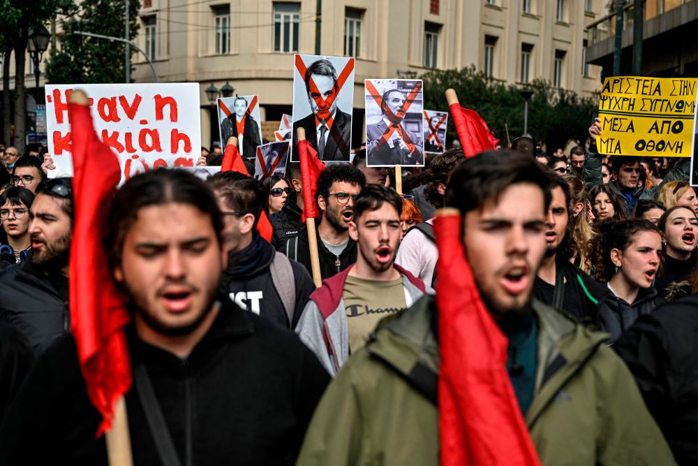 Protesters, including some holding placards with officials’ portraits marked with a red cross such as Greek Prime Minister Kyriakos Mitsotakis (C), take part in a demonstration against the government and to voice outrage at the February 28, 2023, train disaster during a 24-hour strike, in Athens on March 16, 2023. AFPPIX