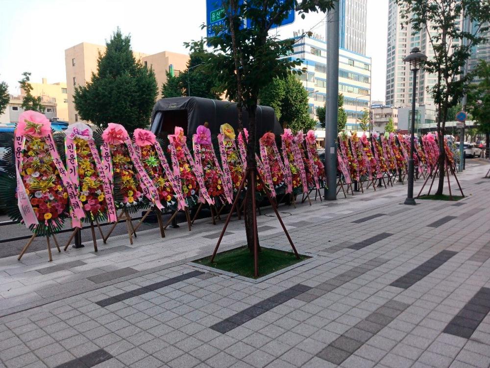 $!Flower wreaths calling for Suga’s withdrawal from BTS were displayed outside the Hybe building. – PIC FROM X @PANCHOA