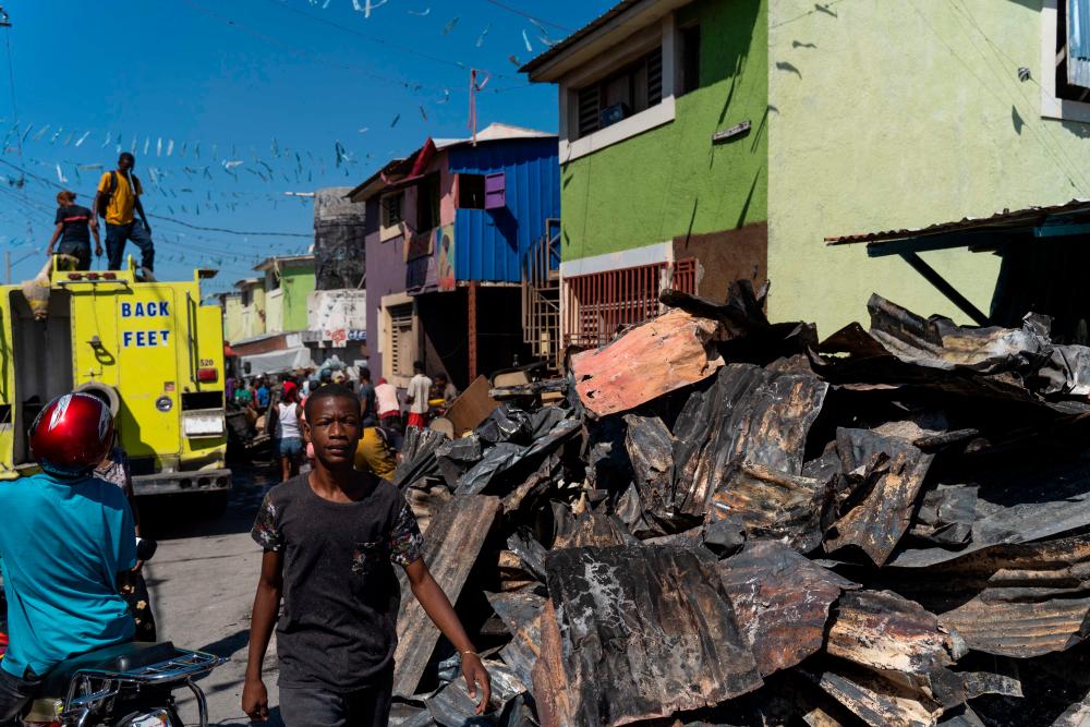 A young man walks past debris following a fire in a popular neighborhood of Port-au-Prince, Haiti, on January 23, 2023. AFPPIX