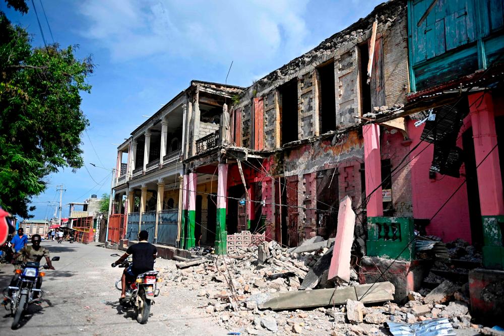 Orang ramai memandu melepasi bangunan yang rosak di Jeremie, Haiti, selepas gempa bumi melanda barat Haiti. fotoAFP