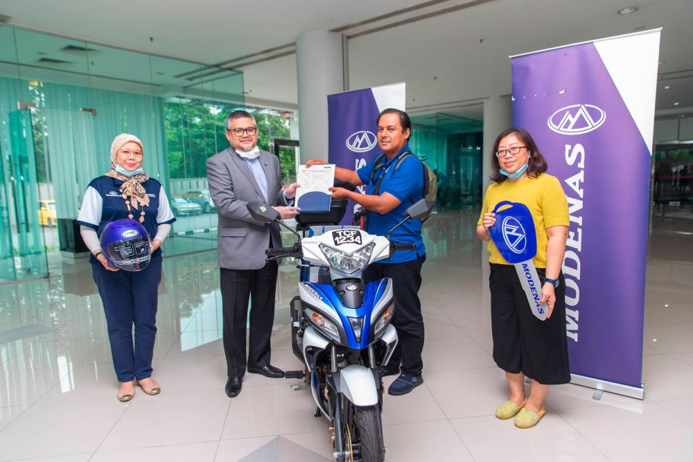 A joyful moment - Mohammad Azhar (in blue) receiving his Modenas CT 115S from Mahmood Abd Razak, Group Head of Strategic Communications of DRB-HICOM. The handing over ceremony was witnessed by Balkish Hood, Head of Marketing and Communications at MODENAS (L) and Angie S Chin, the CEO and Co-founder of Hanafundme.com (R).