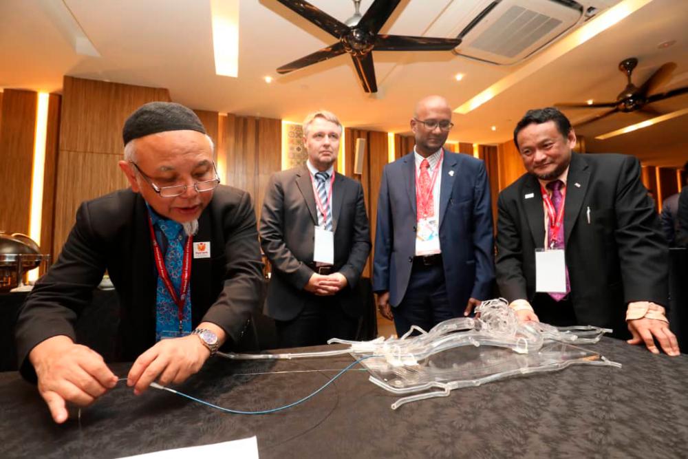 Prof Datuk Dr Wan Azman Wan Ahmad (L) demonstrates the use of sirolimus-coated balloon catheter, as Professor Bruno Scheller (2nd L) and Datuk Dr Rosli Mohd Ali look on, during a conference at the Sheraton in Petaling Jaya, on July 26, 2019. — Sunpix by Masry Che Ani