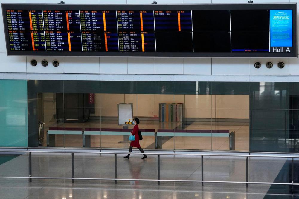 A flight attendant walks under an information board at the arrivals hall of Hong Kong International Airport, following infections of the coronavirus disease (Covid-19) in Hong Kong, China January 11, 2022. REUTERSpix