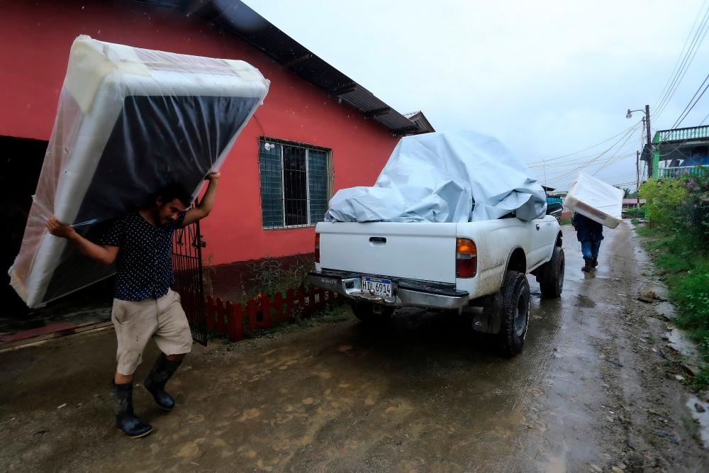 Residents leave their house as the Chamelecon river threatens to overflow in the municipality of La Lima, department of Cortes, Honduras, due to the rains left by Tropical Storm Julia, on October 9, 2022. AFPPIX