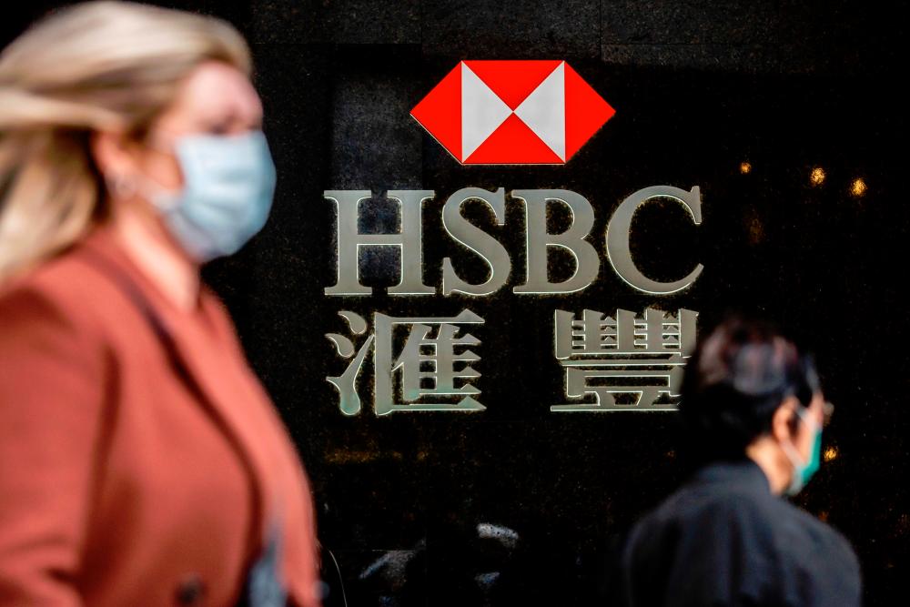 A woman walks past a HSBC sign in Hong Kong today. The lender said today it haS cut its bonus pool for 2019 by 4% to reflect poor performance. – AFPPIX