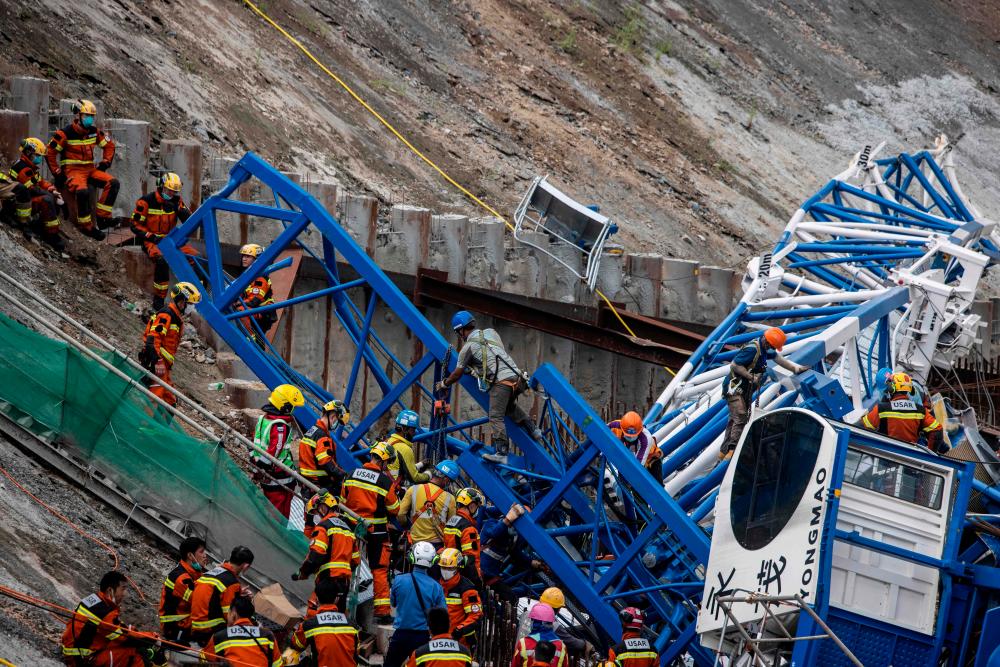 Members of the Urban Search And Rescue (USAR) team (L) work on a collapsed crane in Hong Kong on September 7, 2022, where two people died and six were injured at a construction site. AFPPIX