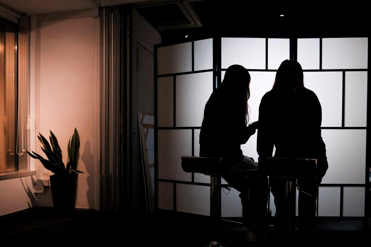 This photo taken on July 29, 2025 shows University of Hong Kong (HKU) students B and C scrolling through their phones in Hong Kong. - AFPPIX