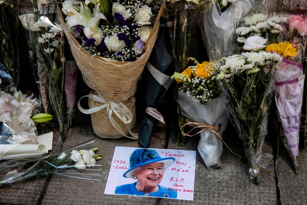 This picture shows flower bouquets and a message left for Britain’s Queen Elizabeth II outside the British Consulate in Hong Kong on September 9, 2022. Queen Elizabeth II, the longest-serving monarch in British history and an icon instantly recognisable to billions of people around the world, died at her Scottish Highland retreat on September 8 at the age of 96. AFPPIX
