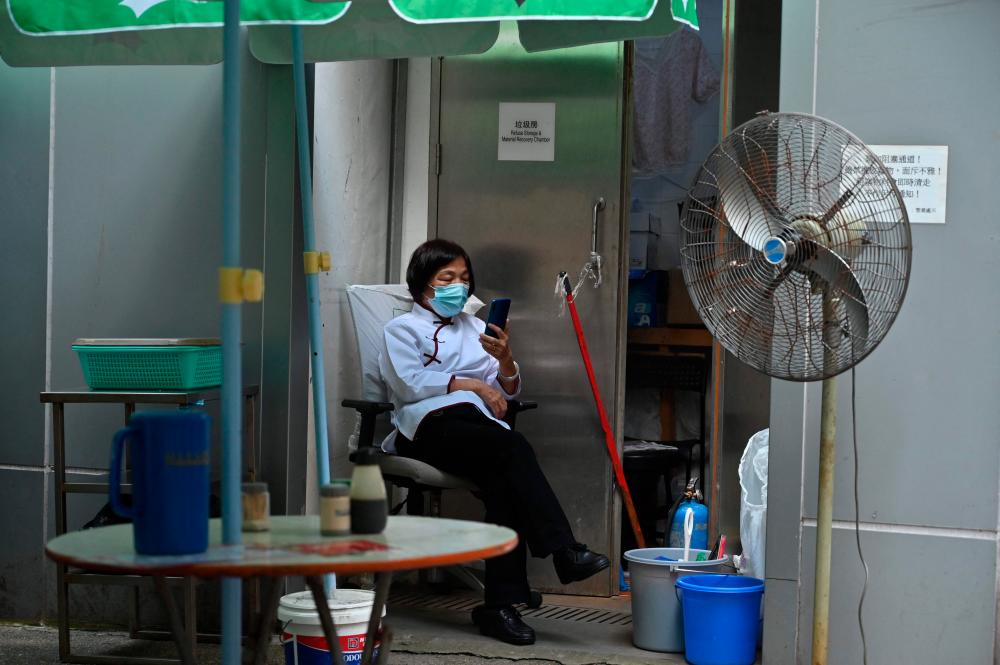 A worker uses her mobile phone on a street in Hong Kong on September 21, 2022. AFPPIX