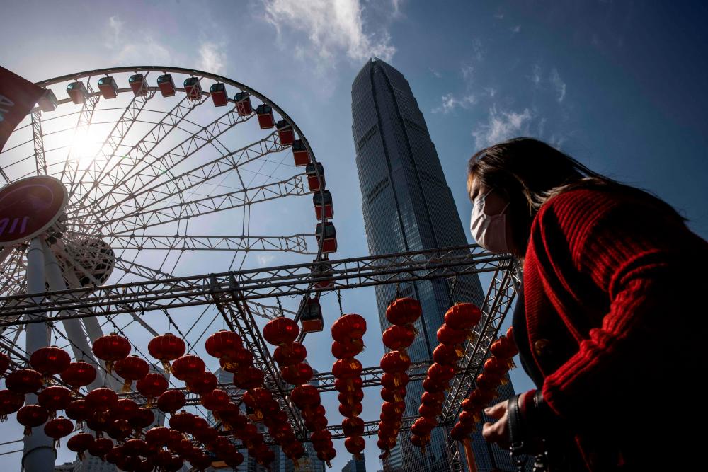A woman walks past an observation wheel in the central district of Hong Kong on February 2, 2023. AFPPIX