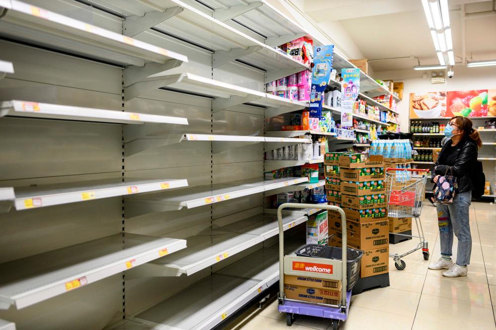 A woman wearing a facemask as a preventative measure following a coronavirus outbreak which began in the Chinese city of Wuhan, looks at empty supermarket shelves, which used for stacking paper towels, in Hong Kong on February 5, 2020. - AFP