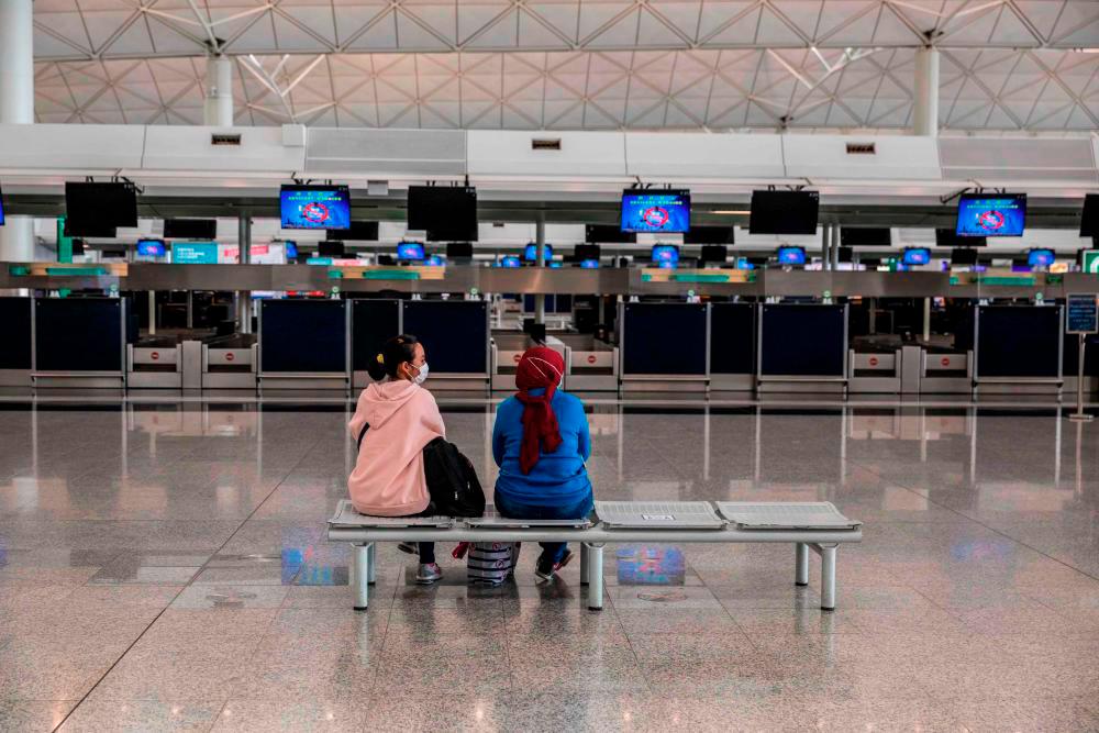 People sit in front of check-in counters at the international airport in Hong Kong on March 21, 2022. AFPPIX