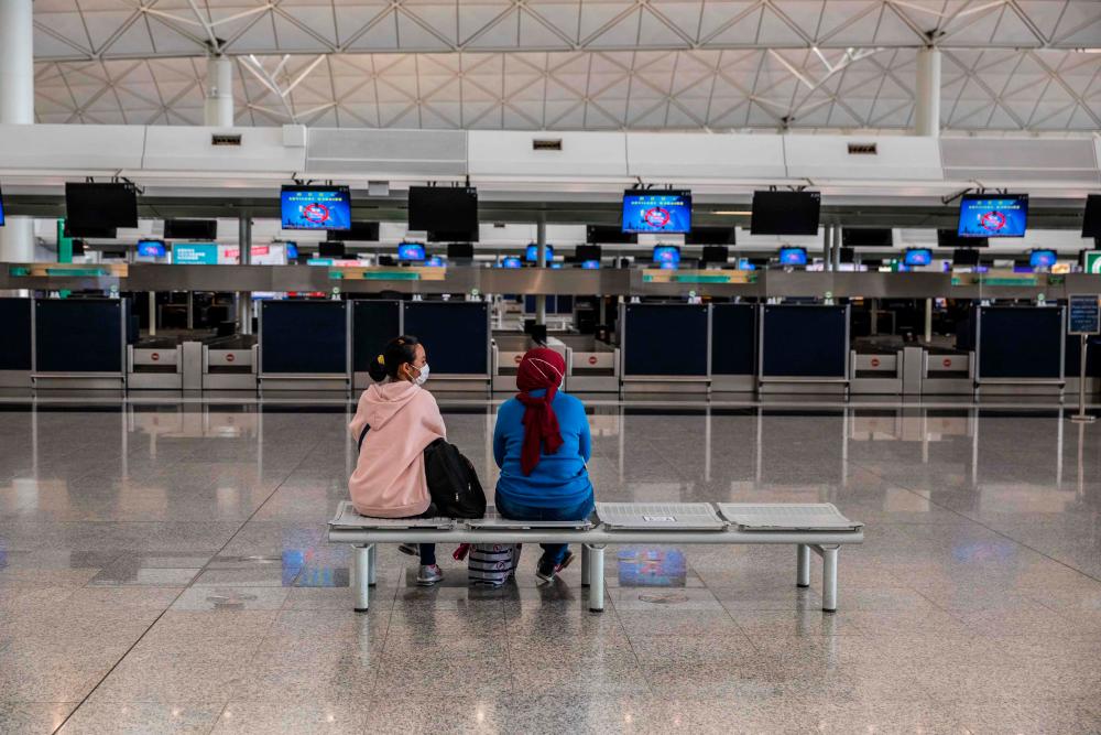 People sit in front of check-in counters at the international airport in Hong Kong on March 21, 2022. AFPPIX
