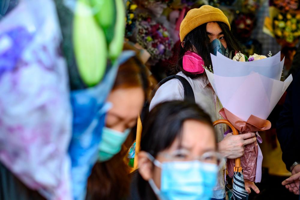 A man wearing a protective face mask as a preventative measure against the Covid-19 coronavirus, buys flowers to mark Valentine’s Day in Hong Kong on Feb 14 - AFP