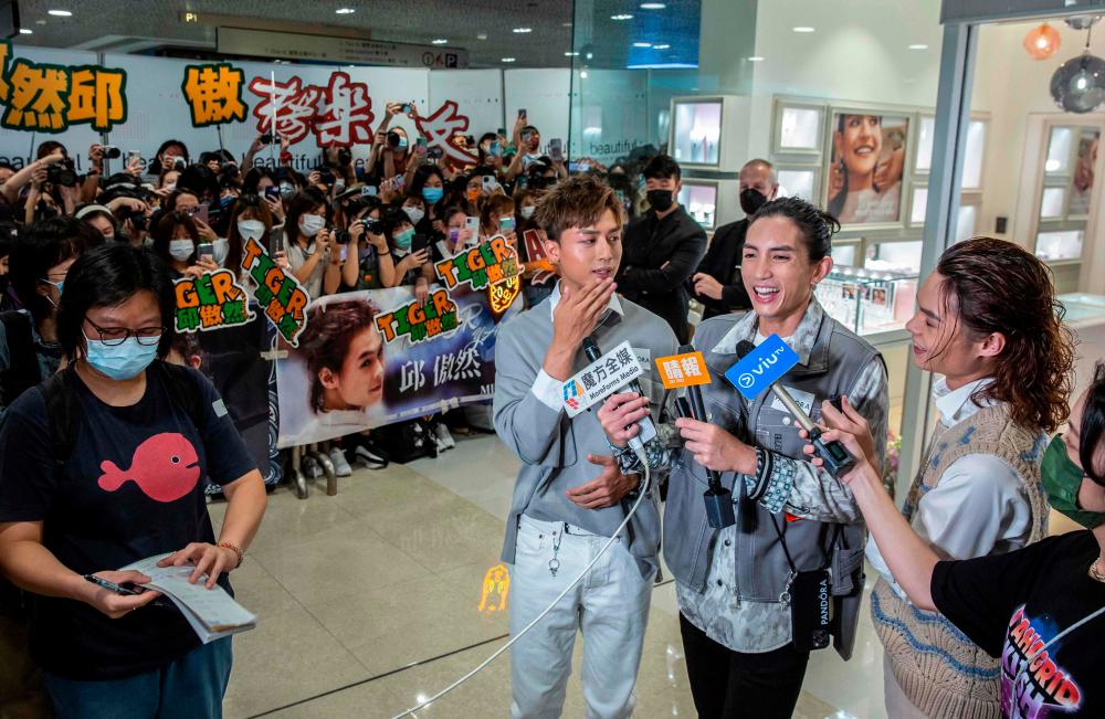 This picture taken on August 5, 2021, shows Anson Kong (C), Lok Man Yeung (2nd R) and Tiger Yau (R), members of Cantopop boyband Mirror, speaking with the media during an event at a shopping mall in Hong Kong. -AFP