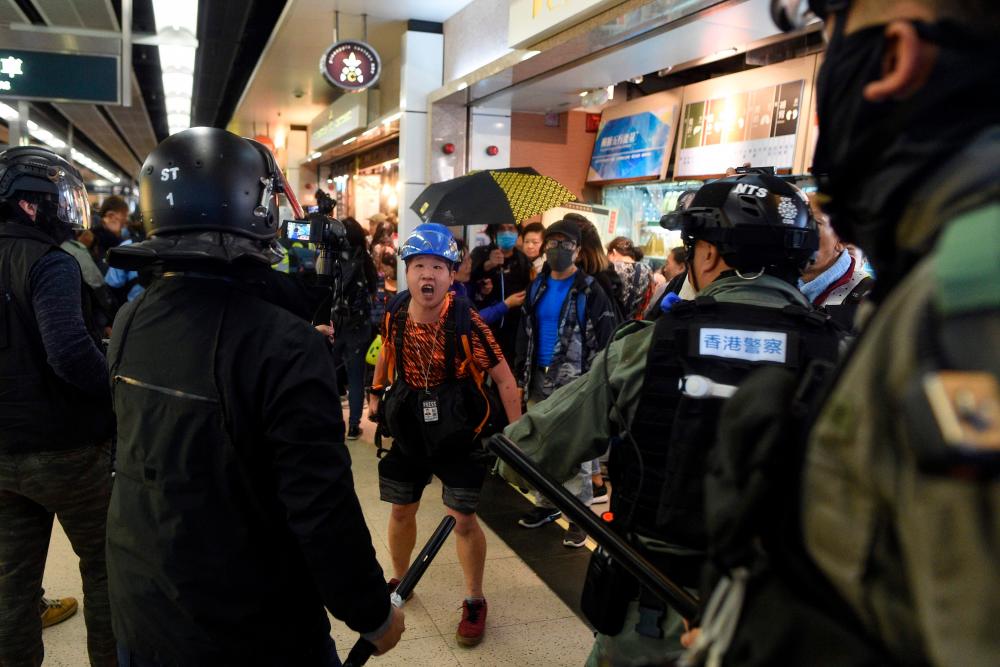 A photojournalist (C) argues with police during a protest at the New Town Plaza shopping mall in Shatin in Hong Kong on December 15, 2019. - AFP