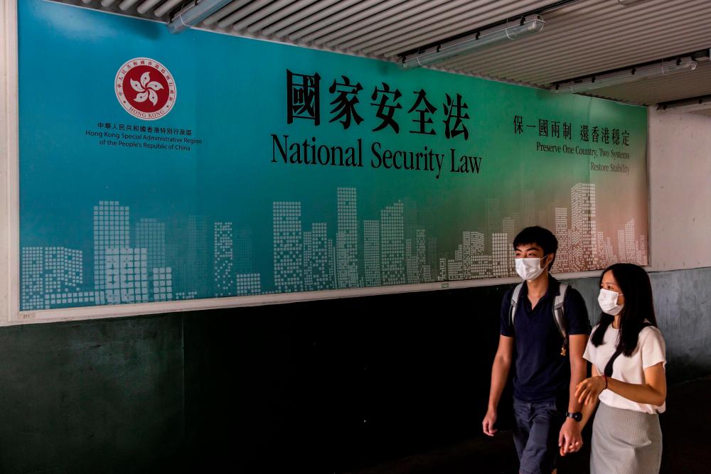 A couple walks past a government advertisement promoting Chinas new national security law in Hong Kong on July 18, 2020. — AFP