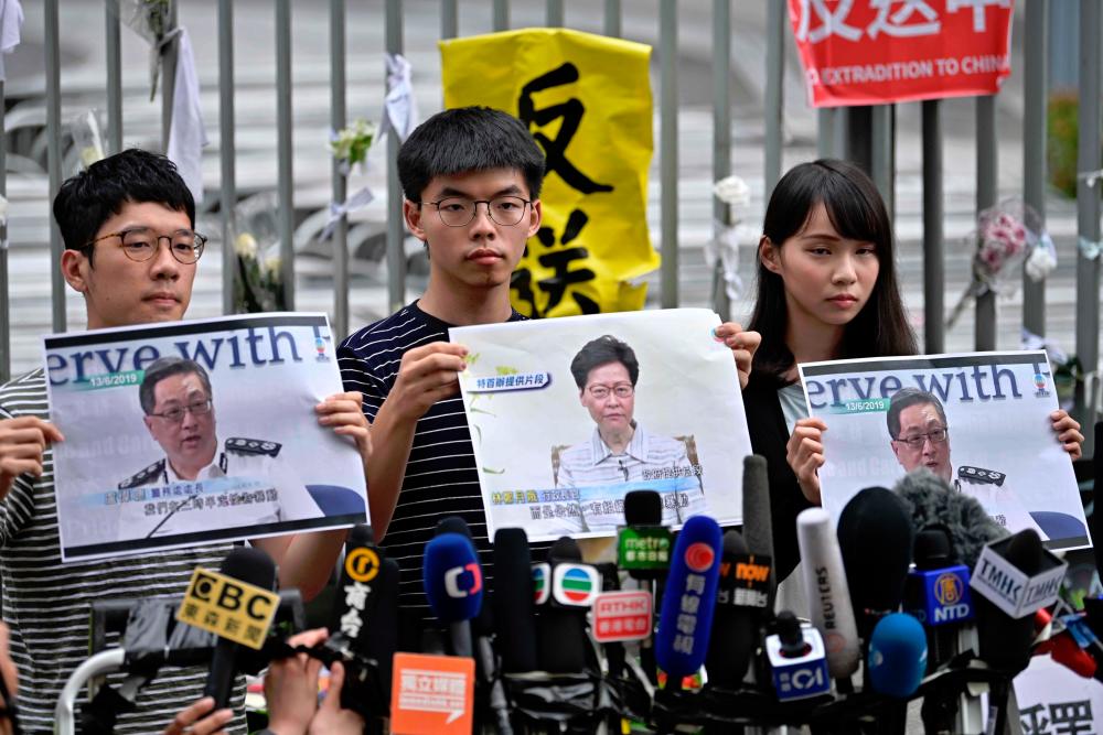 Members of pro-democracy party Demosisto (L-R) Nathan Law, Joshua Wong and Agnes Chow speak to the media after Chief Executive Carrie Lam held a press conference in Hong Kong on June 18, 2019. — AFP