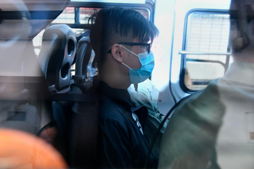 A man (C) wearing a face mask arrives in a police vehicle to the Eastern District Courts in Hong Kong on Oct 7, 2019, where the first protesters arrested for wearing face masks appeared in court. — AFP