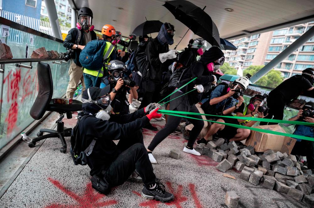Protesters use a catapult against police during a protest Hong Kong's City University on Nov 12, following a day of pro-democracy protests. — AFP