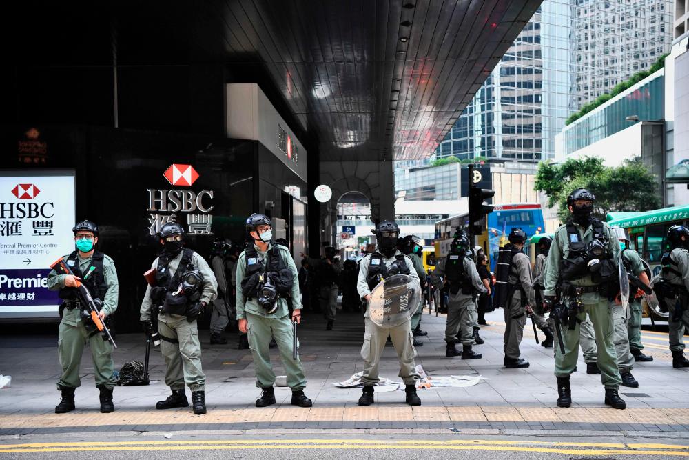 Hong Kong riot police conduct operations to clear away people gathered in the Central district of downtown Hong Kong on May 27, 2020, as the city's legislature debates over a law that bans insulting China's national anthem. A few hundred protesters chanted slogans during a lunchtime rally in the city's Central district but dispersed when officers fired multiple rounds of irritant-filled pellets, AFP reporters on the scene said. - AFP