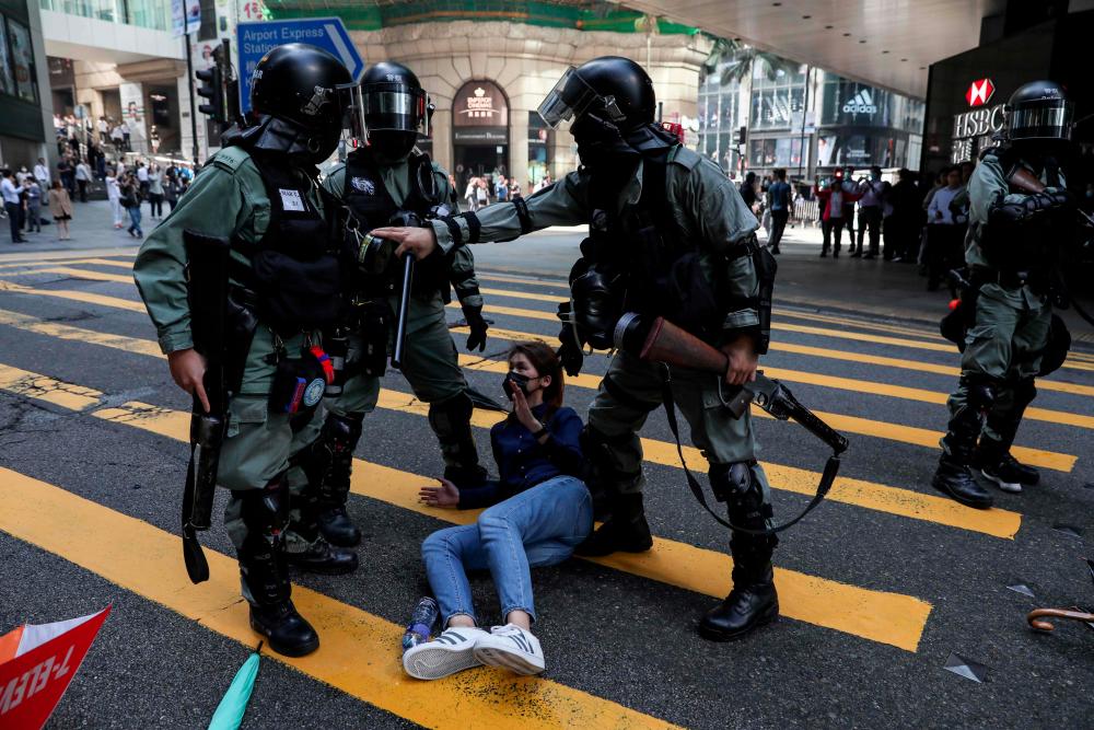 Police detain a woman during a flash mob to block roads in the Central district in Hong Kong on Nov 13. — AFP