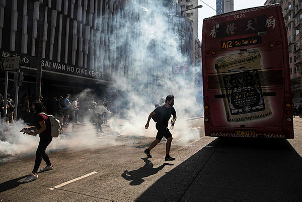 Protesters react after police fire tear gas to disperse them in the Sai Wan Ho district in Hong Kong today. — AFP