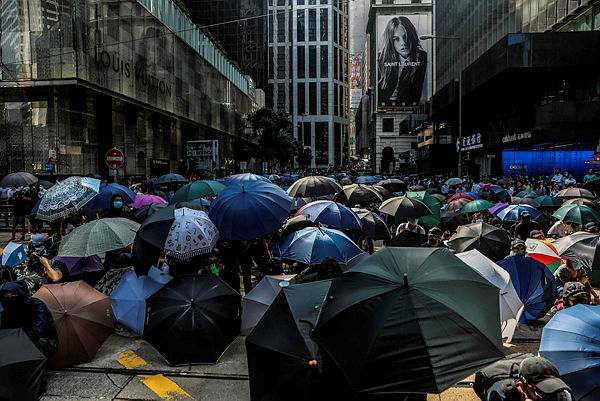 Demonstrators shield beneath umbrellas as police arrive during a flash mob protest in the Central district in Hong Kong on Nov 13 2019 — AFP