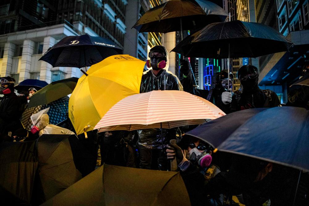 Protesters look on from Pedder Street in Central following a pro-democracy rally from Victoria Park to Chater Road in Hong Kong on Dec 8. — AFP