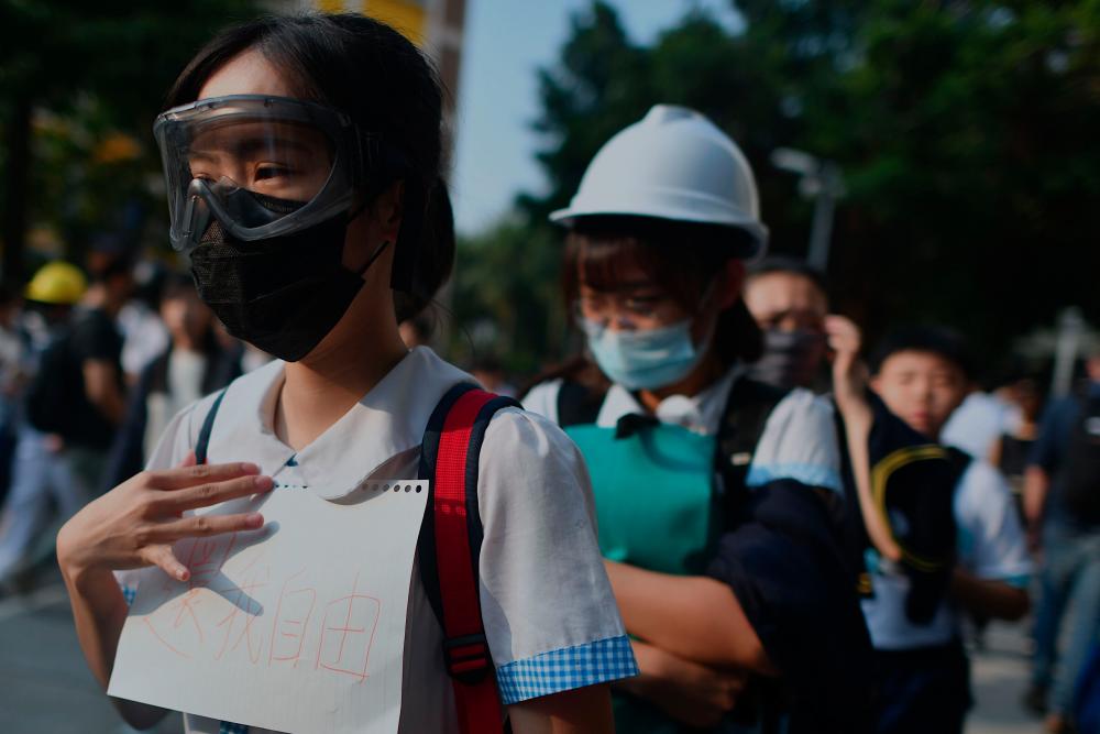 A pupil (L) holds a placard that reads return freedom to me in support of form five student Tsang Chi-kin, 18, who was shot in the chest by police during violent pro-democracy protests that coincided with China's Oct 1 National Day, during a protest at a school in Hong Kong on Oct 2, 2019. — AFP