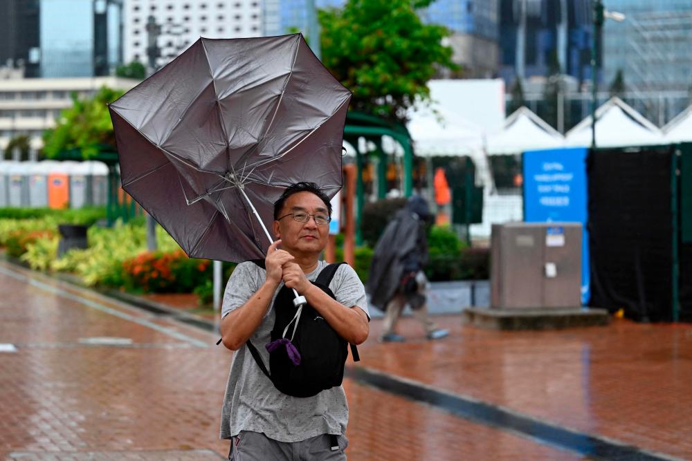 A man has his umbrella turned inside out as Hong Kong hoisted typhoon signal no 8 around noon on October 8, 2023 as typhoon Koinu skirted by after the financial hub was affected again by a super typhoon and historic rainstorm last month. AFPPIX