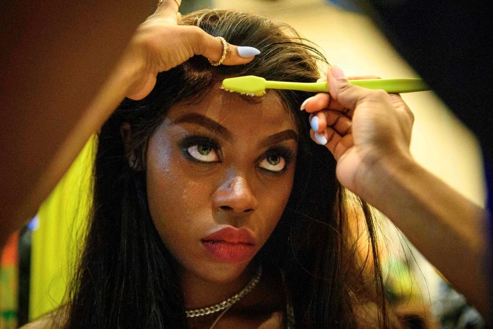 This picture taken on November 6, 2020 shows Harmony Anne-Marie Ilunga, 22, who moved to Hong Kong as a child refugee from the Democratic Republic of Congo, having her makeup applied in the backstage area before the ‘Harmony IV’ fashion show in Hong Kong, which aims to celebrate the city’s diversity. - AFP / Anthony WALLACE
