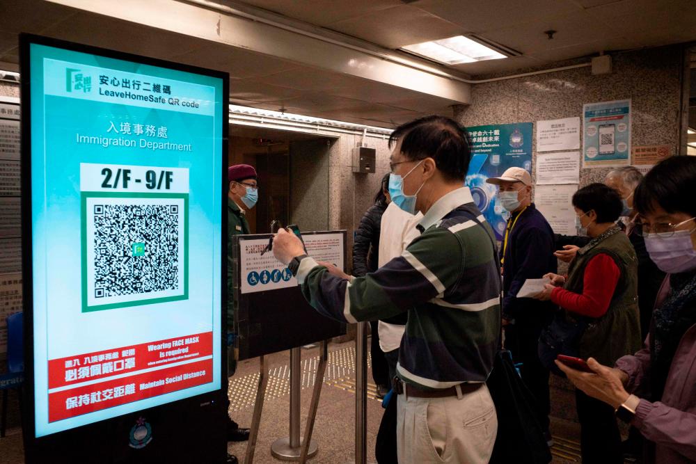 A man scans a QR code for the government's 'Leave Home Safe' app, used for contact tracing amid the Covid-19 pandemic, to enter Immigration Tower in Hong Kong on December 9, 2021. AFPpix