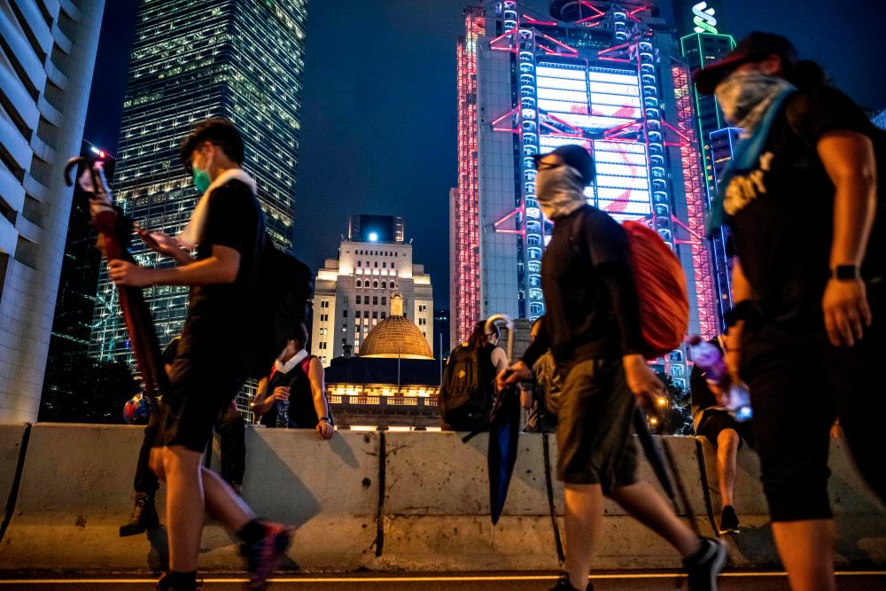 Masked people walk during a protest against police violence and a proposed extradition bill in Hong Kong on July 21, 2019. — AFP
