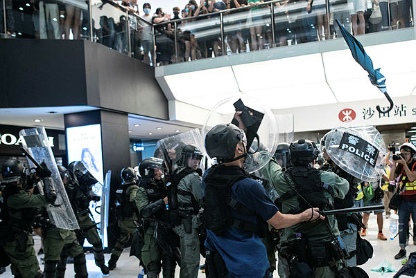 Police officers run as umbrella is dropped by the protesters during a clash inside a shopping arcade in Sha Tin of Hong Kong on July 14, 2019..