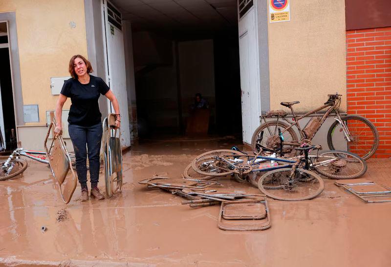 A woman carries out folding chairs caked in mud after torrential rains caused flooding in La Alcudia, Valencia region - REUTERSpix