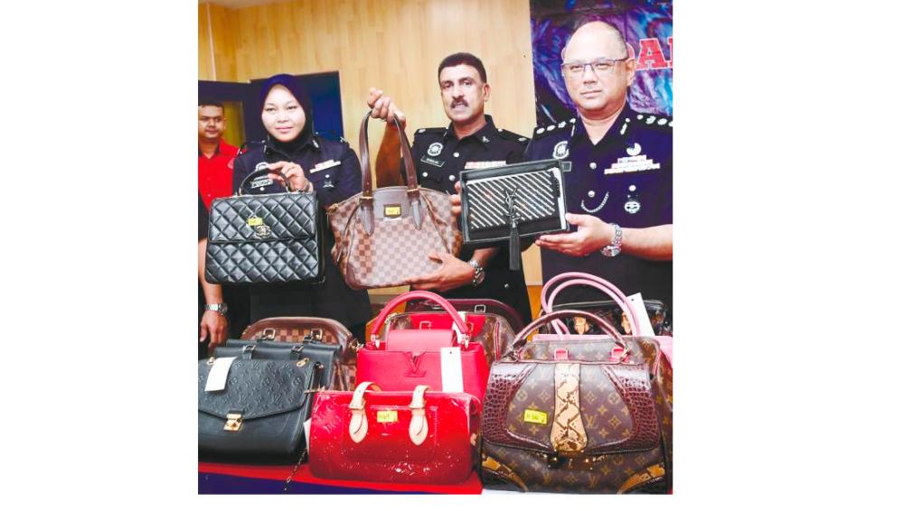 Dang Wangi district police chief ACP Mohd Fahmi Visuvanathan (right) shows branded handbags yesterday that were seized from a former army personnel who stole 70 handbags worth RM250,000 from an outlet in a shopping complex in Kuala Lumpur. — Bernama