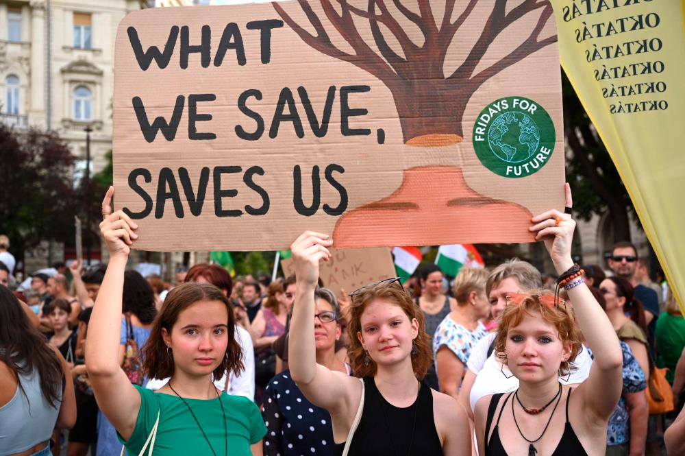 Young girls hold up a placard as they protest against the newly passed deforestation law, in front of the parliament building in Budapest, on August 12, 2022. AFPPIX