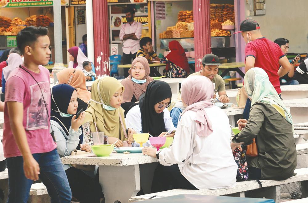 $!NO SOP? ... These youngsters seem to have thrown caution to the wind, ignoring the requirement for social distancing as they dine in the open at an eatery in Padang Kota, George Town yesterday. – MASRY CHE ANI/THESUN
